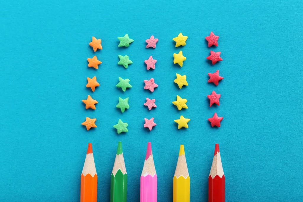 five columns of five cutout stars above five colored pencils